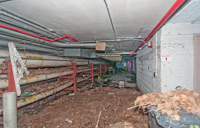 Basement corridor with overhead pipes and debris left after flooding